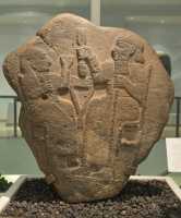 3 Stèle funéraire néo-hittite (10°-8°sBC - Marash, Syrie - Basalte) Couple attablé devant des galettes de pain. L'homme tient un épi de blé et la femme une coupe